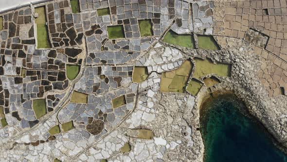 Ascending aerial drone shot of the Salt Pans on the island of Gozo in the Maltese Archipelago.
