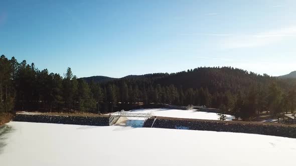 Flying up revealing huge beautiful, hidden frozen lake in Colorado forest.