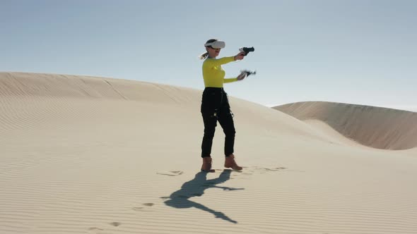 Energetic Young Woman in Virtual Reality Headset Playing VR Shooter at Dunes