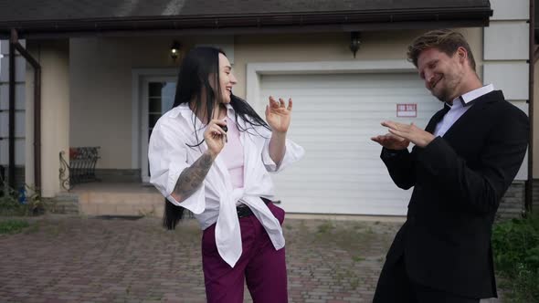 Excited Wife and Husband Dancing in Slow Motion Rejoicing Purchase of New House Outdoors