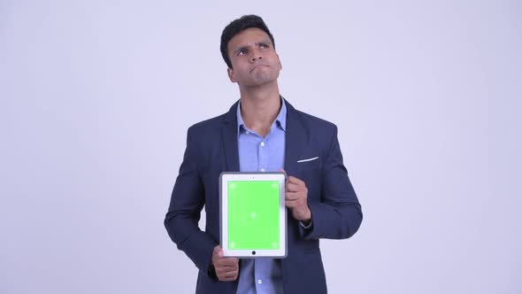 Happy Young Indian Businessman Thinking While Showing Digital Tablet