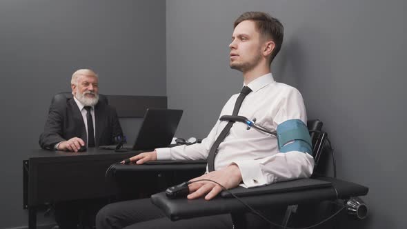 Senior Expert Checking Handsome Man with Computer Polygraph