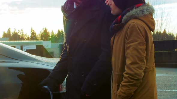 Couple talking while charging the electric car on a winter day