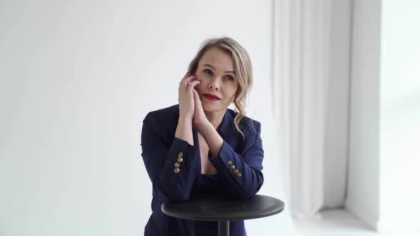 A Blonde Woman in a Blue Suit Poses in a Photo Studio