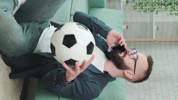 Man Standing with Soccer Ball in Hands and Talking on the Phone