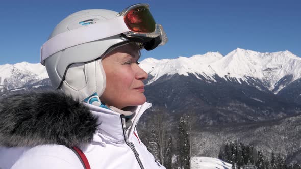 Portrait Of Female Skier On Background Of Snowy Mountains In Winter