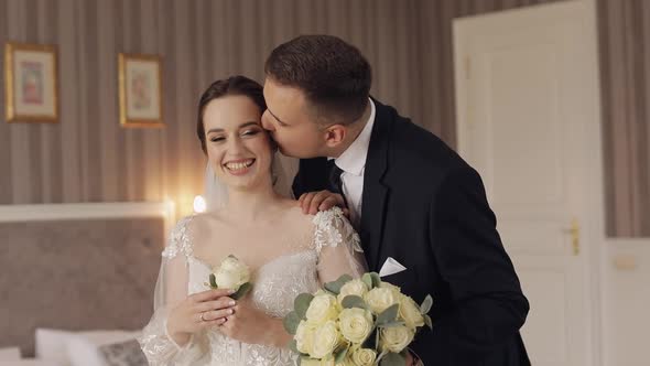 Newlyweds Young Caucasian Bride and Groom First Meeting at Wedding Day Making a Kiss Indoors