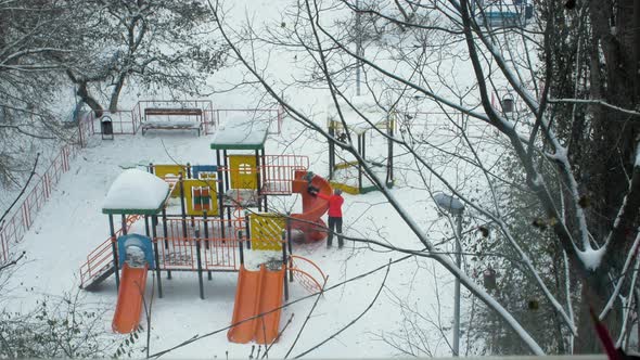 Mom and kid having fun on playground in winter