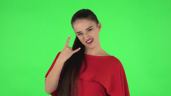 Portrait of Pretty Young Woman Is Making a Rock Gesture and Enjoying Life. Green Screen