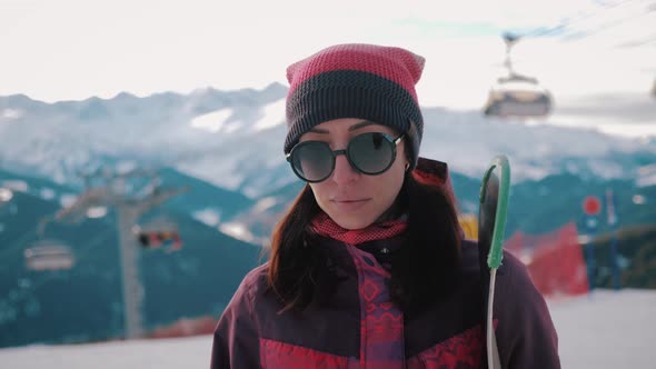 Girl Snowboarder Holding Snowboard in Hands at the Ski Resort. Sport Woman in Snowy Mountains. Sunny