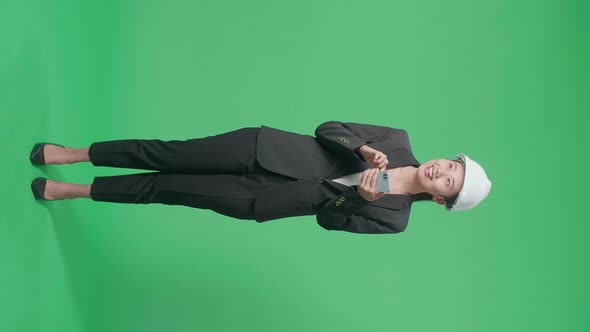 Full Body Of Female Engineer Looking Around And Shaking Head While Using Smartphone On Green Screen