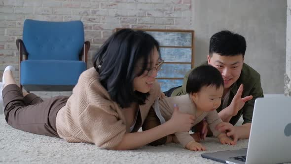 Mother father lie on floor in living room with laptop communicate with relatives