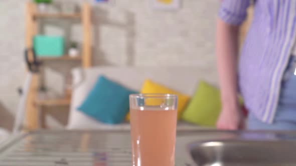 Young Woman Pours Dirty Tap Water Into a Glass