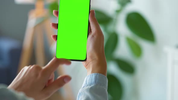 Woman at Home Using Smartphone with Green Mockup Screen in Vertical Mode