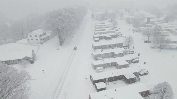 Drone view over rural highway and neighborhood during a snowstorm.