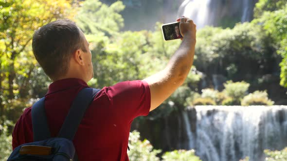 Young Man Blogger Vlogger Record Selfie Video Movie Outdoors on Smartphone Looking at Camera Talking