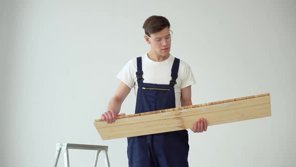 The Floor Installer Holds a Parquet or Vinyl Board and Installs the Flooring