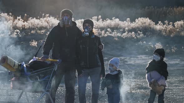 Survivor family in gas mask going through clouds of toxic smoke in desolate and burned landscape.