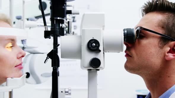 Optometrist examining female patient on slit lamp