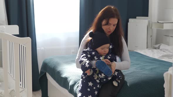 Mother Dressing the Baby in Warm Clothes for a Walk in Winter