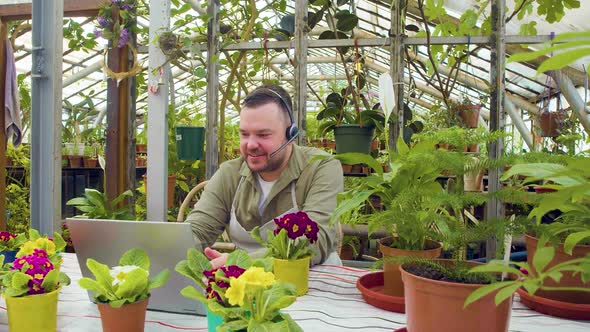 A Young Greenhouse Worker During an Online Video Call He Sitting in Front of Laptop and Telling