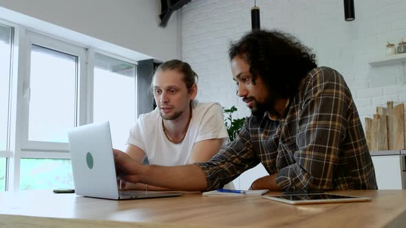 Two Young Freelance Guys Work Remotely At Home on an Online Project, Using a Laptop