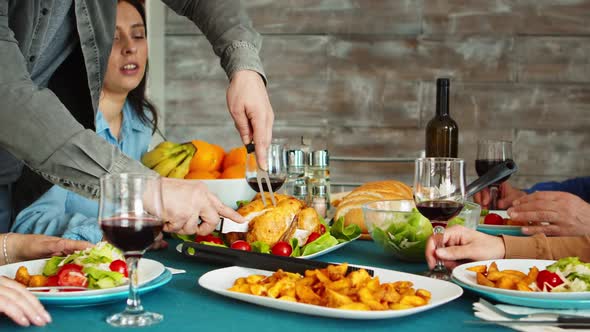 Zoom in Shot of Young Man Using Sharp Knife To Slice Roasted Chicken