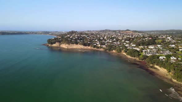 Drone lowering over ocean water to show clifftop properties