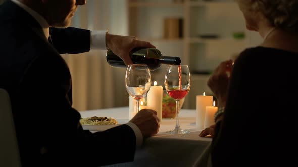 Aged Husband Pouring Red Wine, Romantic Couple Drinking, Celebrating Anniversary