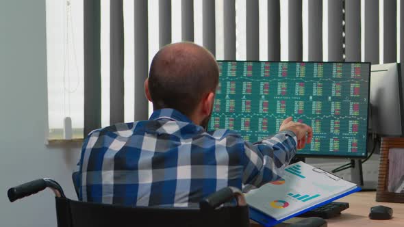 Man Checking Graphs Sitting Immobilized in Wheelchair