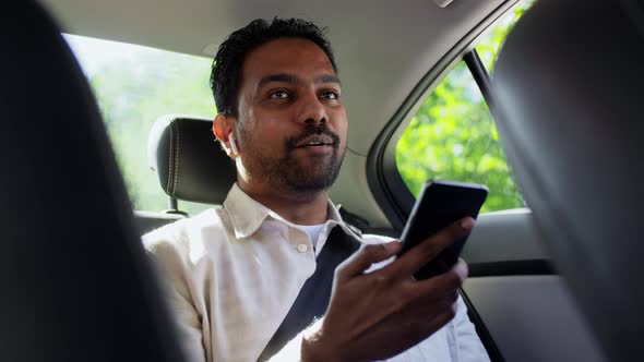 Indian Passenger with Earphones and Phone in Car