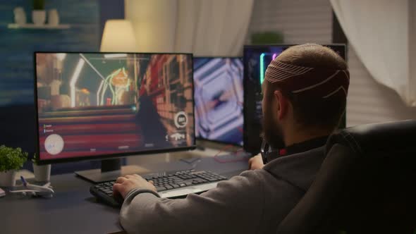 Back View of Pro Man Gamer Sitting on Gaming Chair at Desk