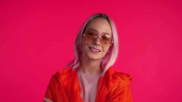 Portrait of beautiful offbeat girl with pink unusual hairstyle in crimson studio.