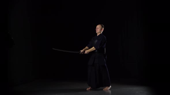 Kendo Warrior Practicing Martial Art with the Katana Sword on Black Background