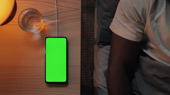 Man Lying in Bed and Touching Green Mobile Screen