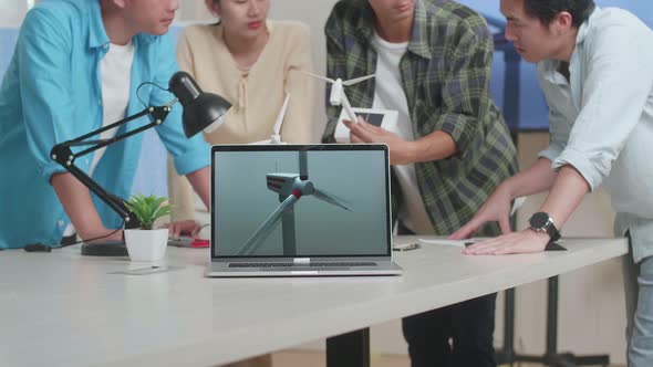 Laptop Showing The Video Of Wind Turbine While Asian Engineers Group Discussing About Work