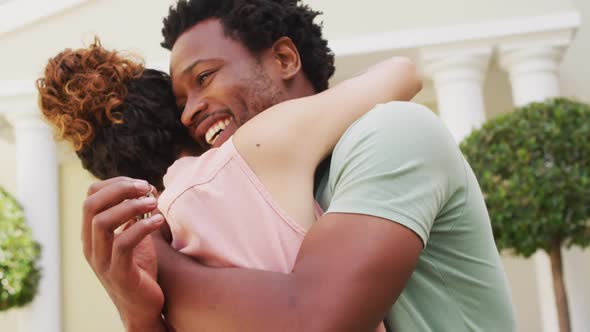 Happy biracial couple embracing with joy in front of new house