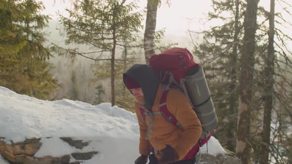 Tourist Climbing Mountain Trail with Trekking Poles in Winter