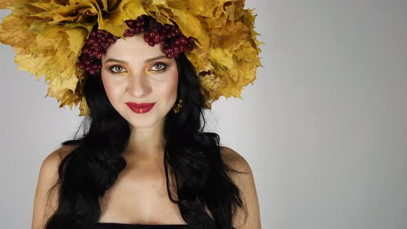 Beautiful Black Haired Girl with Bright Autumn Wreath of Leaves and Flowers Smiling in Studio
