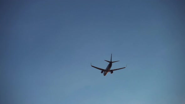 Silhouette of Plane Flying Through Evening Sky