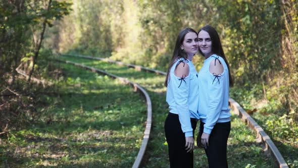 Smiling Young Twins Women Standing Together on Railroad