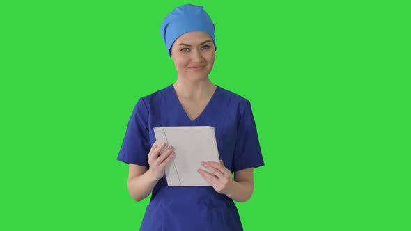 Smiling Female Nurse Using Tablet Computer Walking and Looking at Camera on a Green Screen, Chroma