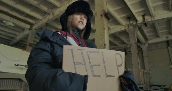 Ukrainian Refugee in Dirty Winter Clothes Standing with the Help Cardboard and Asking for Help