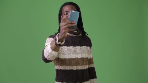 Young Handsome African Man with Dreadlocks Against Green Background