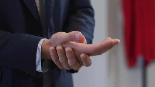 Mid section of man sanitizing his hands at office