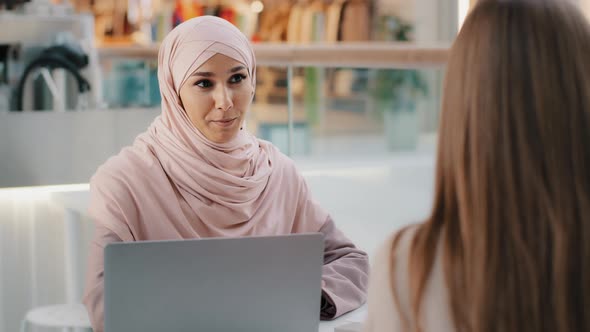 Young Arab Woman Consultant Sales Agent Bank Worker Sitting at Office Desk Advises Unrecognizable