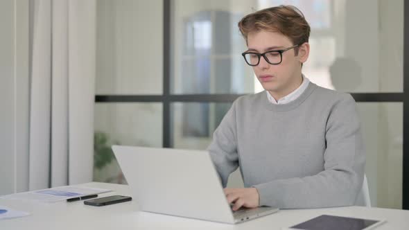 Young Man Closing Laptop and Leaving Modern Office