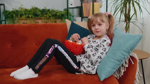 Shocked Children Girl Watching Comedy Video Tv Program or Movie Film Content on Tv Eating Popcorn