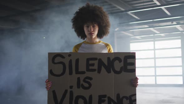 Portrait of african american woman holding protest placard in empty parking garage in empty parking