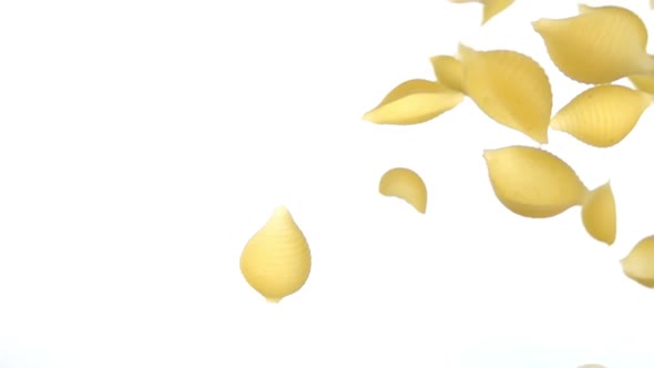 Pasta Conchiglie is Falling Diagonally on a White Background